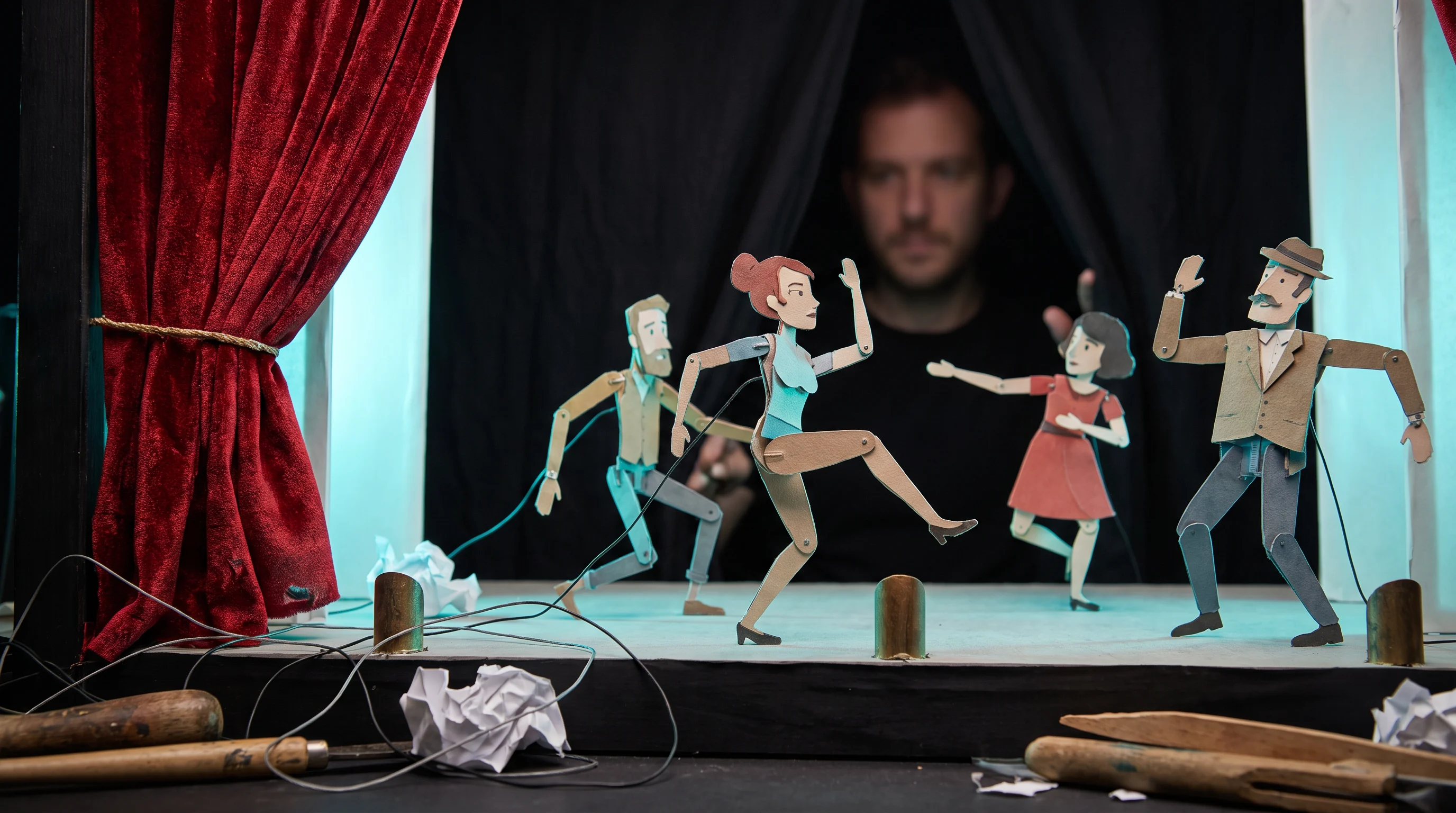 Paper puppet characters posed on a theatre stage